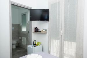 a bathroom with a toilet and a television on a wall at Punta mare in Marsala