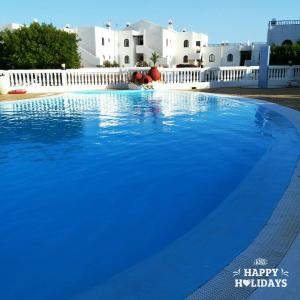 a large blue swimming pool with white buildings in the background at The Colors House, 513 nice and cosy in Costa Teguise