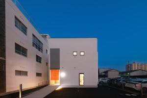 a white building with a door in a parking lot at Hotel QOL 瓦町 in Takamatsu