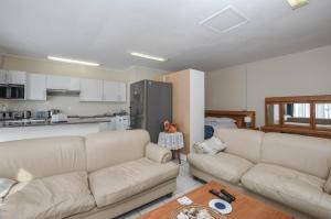 a living room with two white couches and a kitchen at Family Tides Studio in Yzerfontein