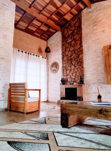 a living room with a stone fireplace and a table at Casa Recanto Beija Flor, Monte Verde in Monte Verde
