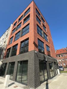 a tall red brick building with windows at Dluga Grobla 6 Apartments Oldtown in Gdańsk