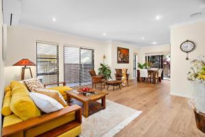a living room with a yellow couch and a table at Villa beach Austinmer in Austinmer