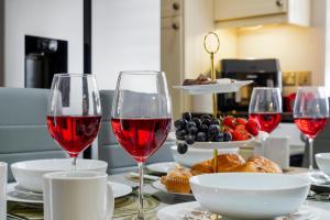 a table topped with glasses of red wine and food at 2 King 4 Singles 2 Sofa Beds Driveway Parking x 3 Private Garden Decking in Hillingdon