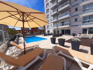 a patio with chairs and an umbrella and a pool at LUX TOWER Punta del Este Port in Punta del Este