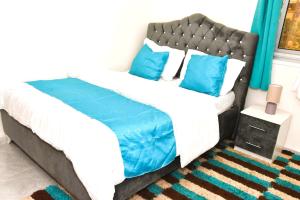 a bedroom with a large bed with blue pillows at Cosy by dalyda in Yaoundé