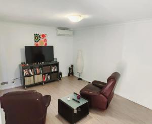 a living room with two chairs and a television at Airport budget room in Perth