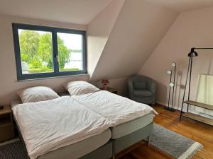 a bedroom with a bed and a chair and a window at Havelhaus Werder in Glindow