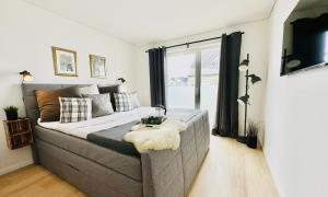 a bedroom with a large bed and a window at Nordlicht, Olpenitz - moderne Ferienwohnung in direkter Strandnähe mit eigenem Eingang, Sauna, Kaminofen, Terrasse und Parkplatz in Olpenitz +32 photos