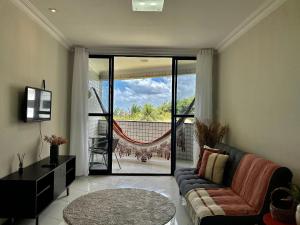 a living room with a couch and a sliding glass door at (104) Litorânea Apartment – Steps from the Beach in São Luís