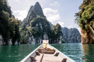 a boat in the water with mountains in the background at khaosok Center Guesthouse in Khao Sok National Park