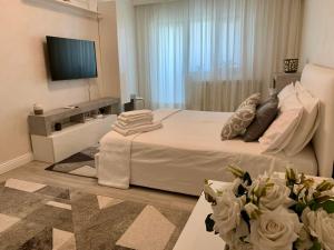 a bedroom with a white bed and a television at Central and beautiful flat in Focşani