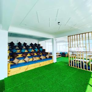 Una habitación con almohadas azules y amarillas y alfombra verde. en Hop Inn Hostels Rishikesh, en Narendranagar