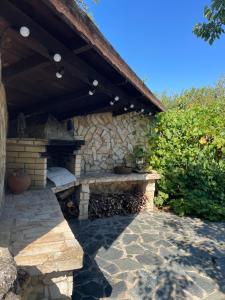 a stone patio with a stone fireplace under a wooden roof at Villa Sunny Day in St. St. Constantine and Helena