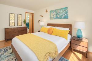 ein Schlafzimmer mit einem großen Bett mit einer gelben Decke in der Unterkunft Mid century modern air conditioned retreat with expansive garden in Lake Forest Park