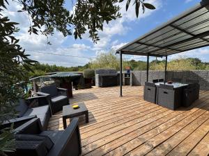 une terrasse en bois avec des canapés et des tables. dans l'établissement Maison villa avec piscine, à Sadirac