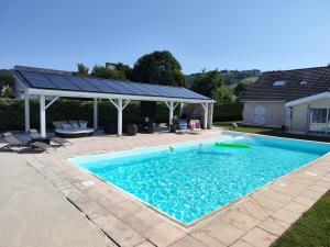 a swimming pool with a pergola next to a house at Villa Sérénité in Allassac