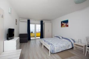 a white bedroom with a bed and a television at Apartmani Ve-Ro in Opatija