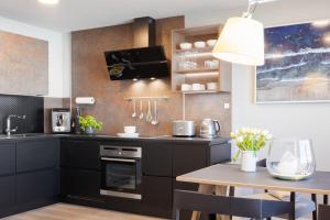 a kitchen with black cabinets and a wooden table at City-Appartment schick, Einzelgarage inkl in Friedrichshafen