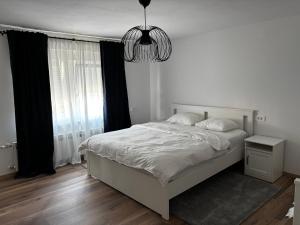 a bedroom with a white bed and a chandelier at Kraljev Vrh Apartments in Kraljev Vrh