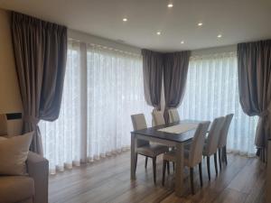 a dining room with a table and chairs and curtains at Holiday House Livigno NEW in Livigno +21 photos