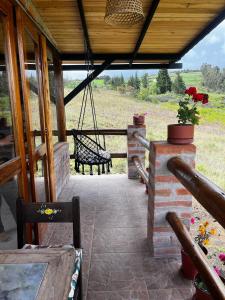 a porch of a house with a swing at Andes Sky Lodge in Hacienda Cochasquí