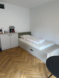 ベルリンにあるSkyline Apartment Adlershof - Premium Design and Full Kitchenの白い壁とウッドフロアの客室のベッド1台分です。