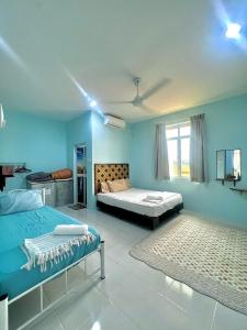 a bedroom with two beds and blue walls at Rembun Homestay, Besut in Kampong Tok Pakir