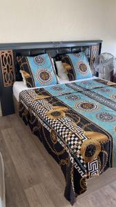 a bed with a blanket and pillows on it at Chambre privative design avec espace salon & cuisine 15 min de Paris in Sarcelles