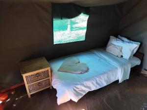 a bed in a tent with a hat on it at Hippo Lagoon Tent On Deck in Maun