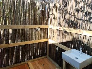 a bathroom with a sink and a wooden fence at Hippo Lagoon Tent On Deck in Maun