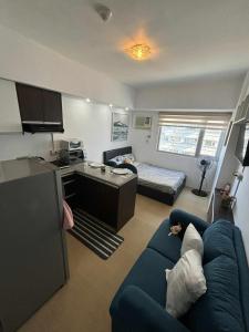 a living room with a blue couch and a bed at Avida tower 2 in Davao City