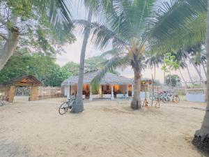 ein Haus mit zwei Palmen im Sand in der Unterkunft TravelLodge Eco in Arugam Bay