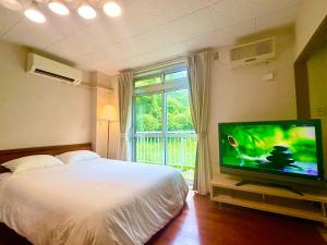 a bedroom with a bed and a flat screen tv at FujiteraCanvas102 in Gotemba