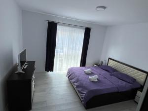 a bedroom with a purple bed and a window at Forest View in Câmpulung Moldovenesc