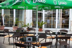 a group of tables and chairs under a green umbrella at Guest house Bohorč in Šentjur