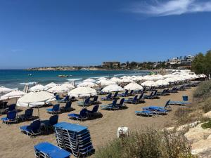 a bunch of chairs and umbrellas on a beach at Aetheria 3BR in Khlorakas