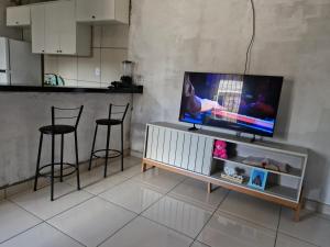 sala de estar con TV y 2 taburetes en Casa aconchegante, en Ananindeua