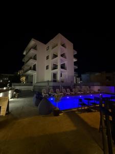 a large building with chairs and a pool at night at Alpha Blue Apartments in Ksamil