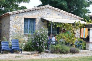 a group of people sitting at a table outside of a house at Maisonette #18, 4 Pers, Domaine De Ribiere in Grospierres