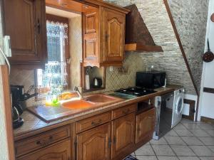 a kitchen with wooden cabinets and a sink and a stove at Maison de Campagne in Trézelles