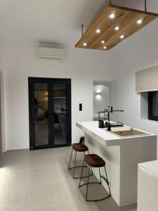 a kitchen with a sink and two bar stools at Deos luxury house in Ios Chora
