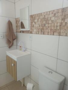 bagno bianco con servizi igienici e specchio di Suíte Park e Mar quarto 2 a Penha