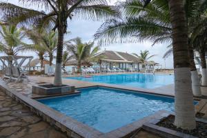 a swimming pool with palm trees in a resort at Ocean Green Beach in Upper Town