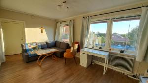 a living room with a couch and a desk and a window at Central och ljus 3-rumslägenhet i Älmhult in Älmhult