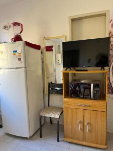 a living room with a refrigerator and a tv at Apartamento kitchenette in São Lourenço do Sul +11 photos