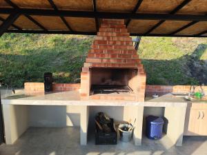 a brick fireplace on a patio under a roof at CasaNatur in Leordina