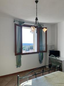 1 dormitorio con ventana con silla y escritorio en Appartamento " Il tramonto ", en Badesi