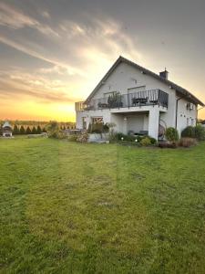 una casa en un campo con la puesta de sol en el fondo en APARTAMENTY Wakacyjna 53 Dziwnówek, Wrzosowo, en Dziwnówek