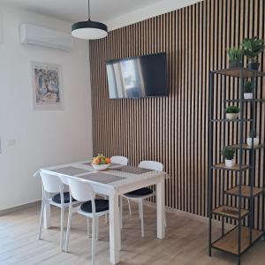 a dining room table with chairs and a television on a wall at Bella Italia in Marina di Strongoli